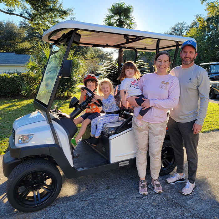 A Family of five enjoying their brand new Bintelli Beyond 4 Seater street legal golf cart in White parked on their driveway