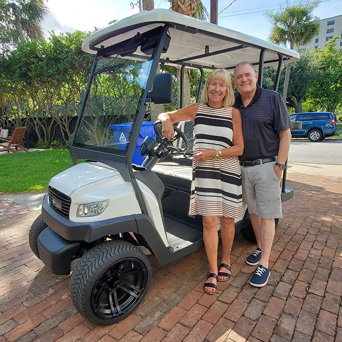 Couple posing with their white Bintelli Golf Cart