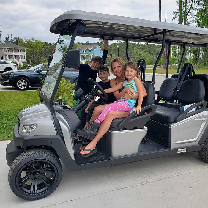 A Family of four enjoying their brand new Bintelli A 6 seater street legal golf cart in Titanium parked on their driveway