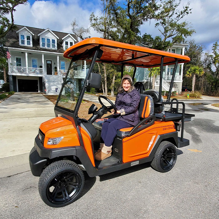 A woman enjoying their brand new Bintelli Beyond 4 Seater street legal golf cart while driving it through town