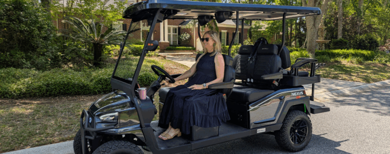 New black Nexus Gen2 being driven by a woman in a black dress on a suburban street.